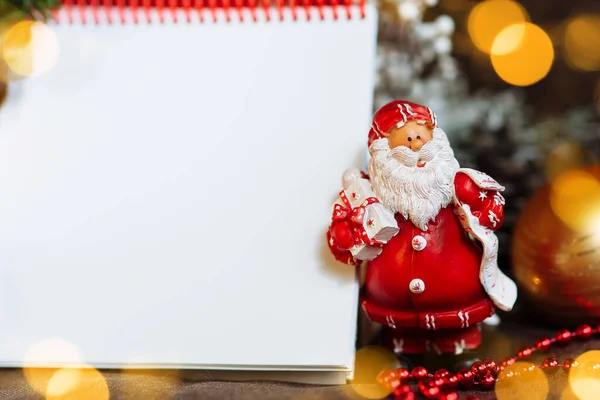 Noel süslemeleri arasında metin için bir boşluk olan not defteri ve Noel Baba maketi