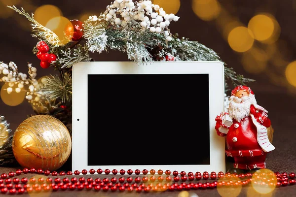 Noel süslemeleri arasında boş ekranlı yatay tablet ve Noel Baba maketi