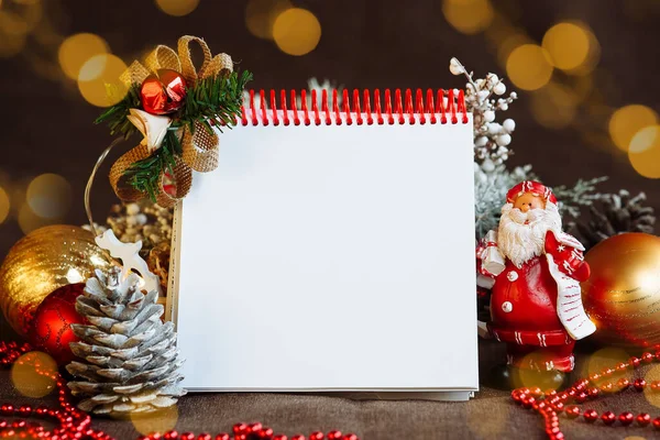 Noel süslemeleri arasında metin için bir boşluk olan not defteri ve Noel Baba maketi