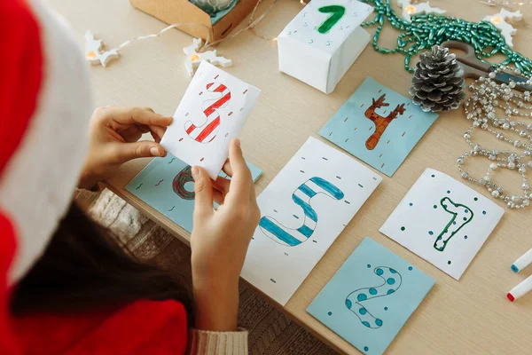 Bir çocuk kendi elleriyle kağıttan bir Noel takvimi hazırlar.