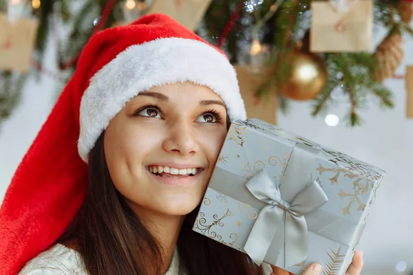 Noel şapkalı gülümseyen kız hediye kutusuyla yakın plan