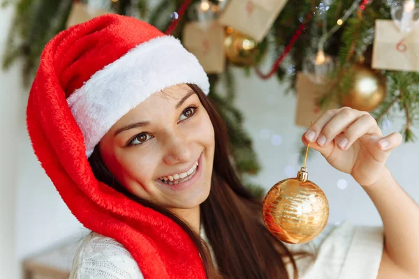 Noel şapkalı mutlu kız elinde Noel ağacı oyuncağıyla.