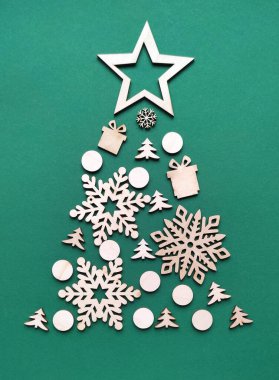 Yeşil arka planda kış ağaçlarından yapılmış Noel ağacı. Tahta kar taneleri, köknar ağaçları, hediyeler. Dikey yönelim.