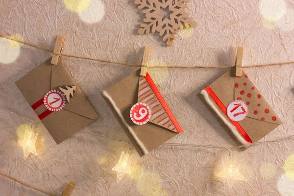 El yapımı, yaratıcı Noel Gelişim Takvimi. Tahta mandallarda asılı Kraft kağıt zarfları.