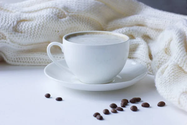 Beyaz kahve fincanı, kahve çekirdekleri ve örgü eşarp. Rahatlama ve rahatlama konsepti.