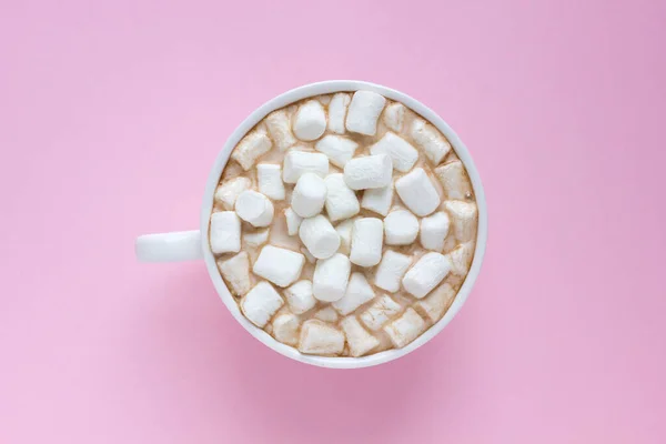 Pembe arka planda kremalı sıcak kakaolu beyaz fincanın üst görüntüsü. Sıcak çikolatalı kupa..