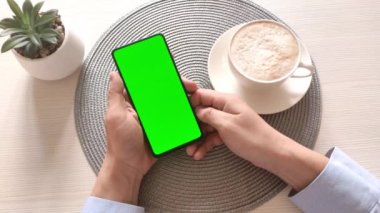Dikey yeşil ekranlı akıllı telefonu tutan ve ekrana dokunan adam. İş konsepti. Chroma Key 'li cep telefonu. Ellerini kapat..