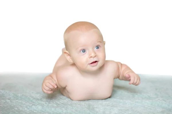Niño sonriente desnudo acostado sobre cuadros azules. Imagen con enfoque escogido y profundidad de campo. —  Fotos de Stock