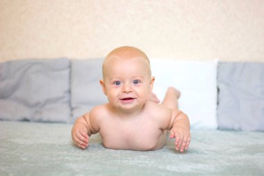 Mavi arka planda yatan çıplak gülümseyen bebek. Seçilen odak ve alanın derinliği ile resim