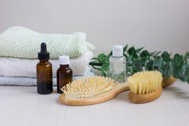 Composition with hair care products, towel and brush on wooden table.