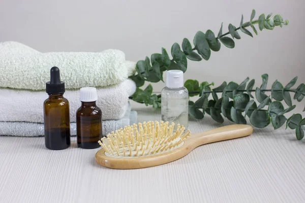 Composition with hair care products, towel and brush on wooden table.