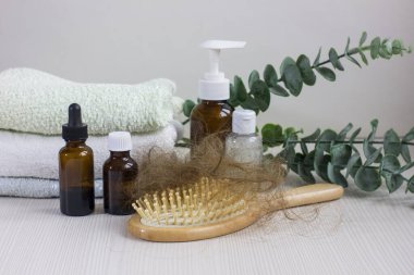 Medication bottles, hairbrush and towel on white wooden table. Concept of hair loss problem.