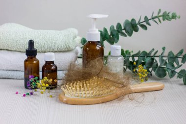 Medication bottles, hairbrush and towel on white wooden table. Concept of hair loss problem.