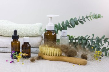 Medication bottles, hairbrush and towel on white wooden table. Concept of hair loss problem.