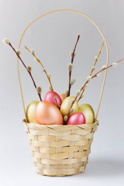 Golden, bronze and pink Easter eggs with pussy willow in basket. Design element for greeting cards, poster or banner.