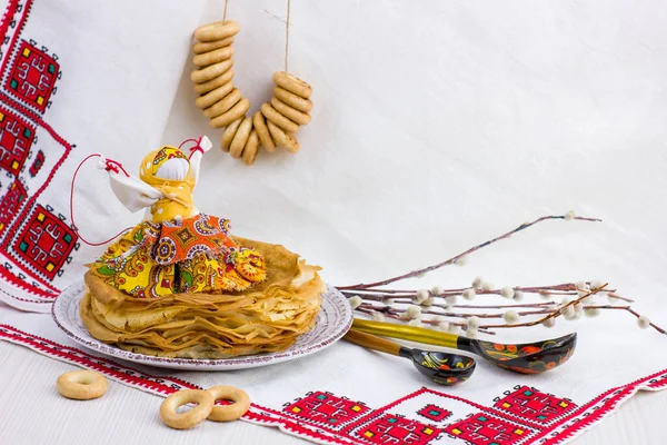 Background with pancakes, textile doll, wooden spoon, rushnik and sushki for Maslenitsa festival. Traditional Russian meal for Shrovetide. Greeting card or poster. Copy space.