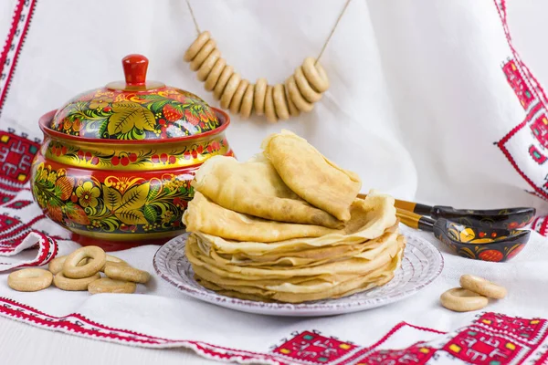 Background with pancakes, wooden utensils with Khokhloma painting, rushnik, sushki for Maslenitsa festival. Traditional Russian meal for Shrovetide. Greeting card or poster. Copy space.