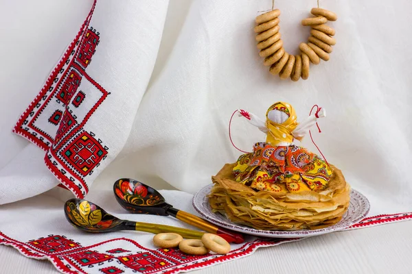 Background with pancakes, textile doll, wooden spoon, rushnik and sushki for Maslenitsa festival. Traditional Russian meal for Shrovetide. Greeting card or poster.