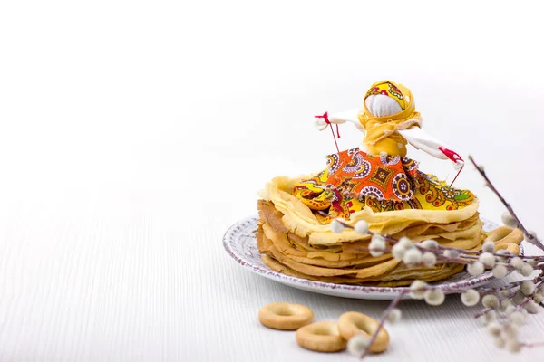 Background with pancakes, textile doll, sushki and pussy-willow on white for Maslenitsa festival. Traditional Russian meal for Shrovetide. Greeting card or poster. Copy space.