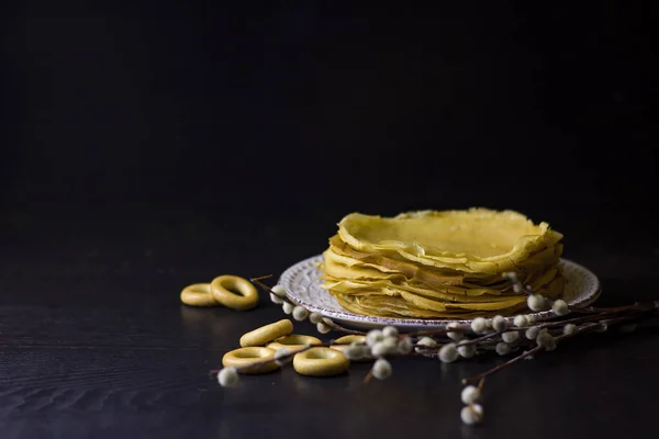 Background with pancakes, sushki, and pussy-willow for Maslenitsa festival. Traditional Russian meal for Shrovetide. Greeting card or poster.Low key. Copy space.