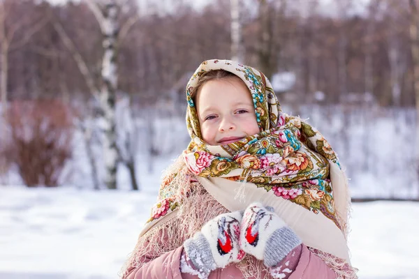 伝統的なロシアのスカーフでかわいい女の子と冬の森の背景にミトン 民俗衣装に身を包んだ子供の肖像 — ストック写真