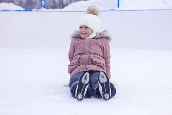 かわいい女の子は秋の後にスケートで氷の上に座って笑う アイスリンクの第一歩 選択的焦点 — ストック写真