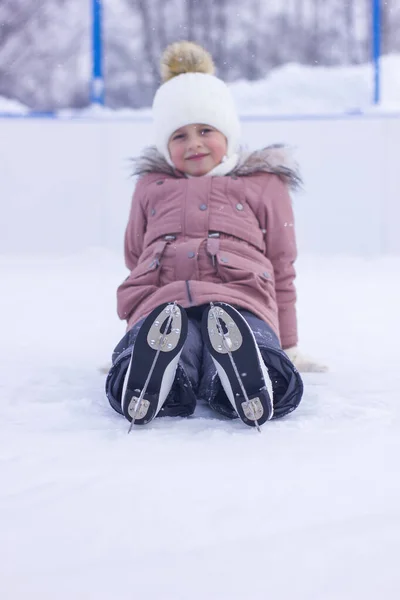 かわいい女の子は秋の後にスケートで氷の上に座って笑う アイスリンクの第一歩 選択的焦点 — ストック写真