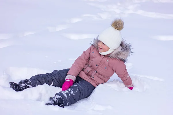 かわいい女の子は雪のドリフトと笑顔にあります 冬の休日のレジャー — ストック写真