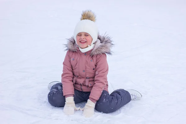 かわいい女の子は秋の後にスケートで氷の上に座って笑う アイスリンクの第一歩 選択的焦点 — ストック写真