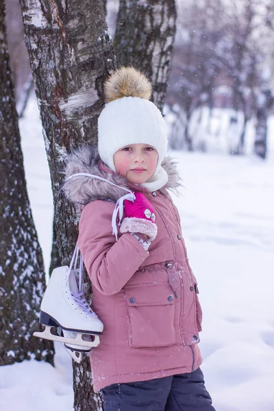 かわいい女の子は屋外でスケートをしようとしている 白樺の木の近くに立って スケートを保持子 冬の休日のレジャーコンセプト — ストック写真