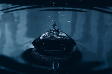 Su, mavi ve koyu su yüzeyine sıçrar ve düşer..