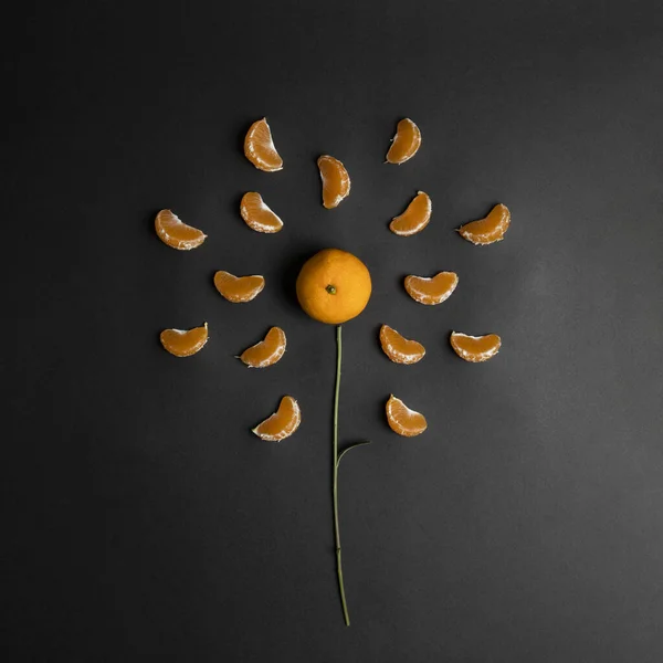 Tangerine in center, with a slice of mandarin around. Like a fruit sun. Black background.