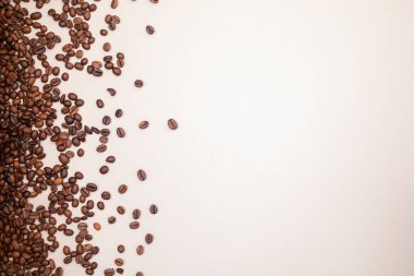 Açık kahverengi arka planda kahve döküldü. Bir sürü kahve. Geçmişi. Kahve çekirdeği.