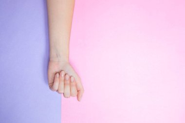 Pembe ve eflatun bir arka plana sarkıtılmış güzel bir kadın eli.