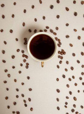 Şemsiyeye doğru kahve dolu bir fincan, kahve çekirdekleri yağmur gibi yağıyor. açık kahverengi arkaplan.