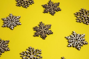 Sarı zemin üzerinde ahşap kar taneleri deseni. Yeni Yıl ve Noel fikri