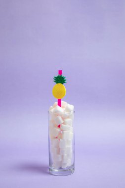 Bir bardak dolusu şeker ve mor arka planda bir pipet. Güzel fotoğraf, ferahlatıcı neşeli fikir. Şeker içeceği.