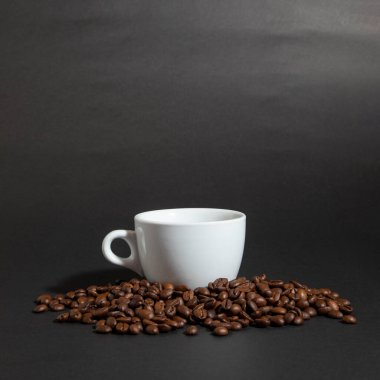 Siyah bir fonda kahve çekirdeği yığını üzerinde bir fincan kahve..