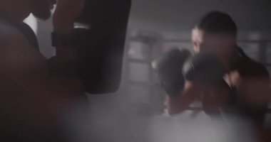 Genç bayan sporcu ve Kafkasyalı erkek boks ringinde antrenman yapıyor. Genç Sporcu Kadın ve Arka Işıkta Kişisel Antrenör. Dövüş Sporu, Yaşam Tarzı.