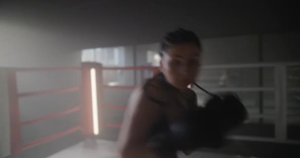 Närbild kvinna tåg slag tittar direkt på kameran. Stark aggressiv ung flicka kvinna boxning i ringen som en symbol för feminism och framgångsrika kvinnor — Stockvideo