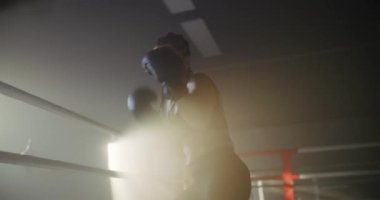 Boks ringinde boks yapan kadın. Kadın Dövüşçü Karanlık Yüzük 'te Yumruk ve Kamera' ya Bakıyor. Kadın Kickboksör Portresi. Boks Konsepti.