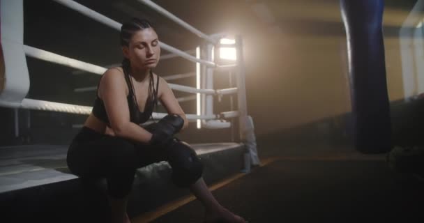 Vrouw zittend in een donkere sportschool en de hand wikkelend met zwart verband. Ik volg een vrouwelijke bokser die zich klaarmaakt voor het gevecht. Begrip sport — Stockvideo