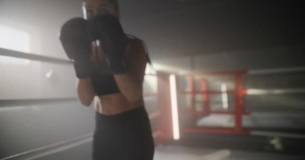 Close Up Woman Trains perfora mirando directamente a la cámara. Mujer joven agresiva fuerte boxeando en el ring como símbolo del feminismo y las mujeres exitosas — Vídeos de Stock