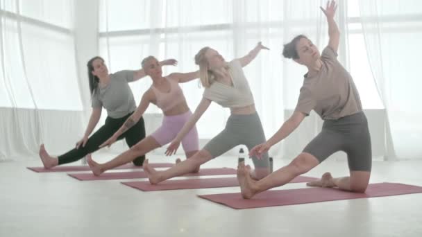 Clase de yoga. Cuatro mujeres haciendo yoga asanas en brillante estudio. Ashtanga Yoga. Un cuerpo relajante. Concepto Salud, Meditación y Bienestar. — Vídeos de Stock