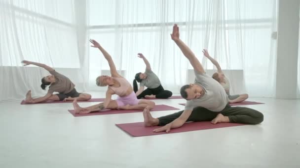 Yoga Class Group of Five Women and Man Exercising Healthy Lifestyle in Bright Studio. Практика йоги с инструктором. Расслабляющее тело. Здоровье, здоровье и благополучие. — стоковое видео