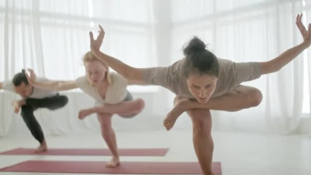 요가 반의 세 젊은 남녀는 균형 운동 과 스 포오츠 요가 를 하고 있다. Group Exercising and Stretching Healthy Lifestyle in Bright Fitness Studio and Gymnastics Class — 비디오