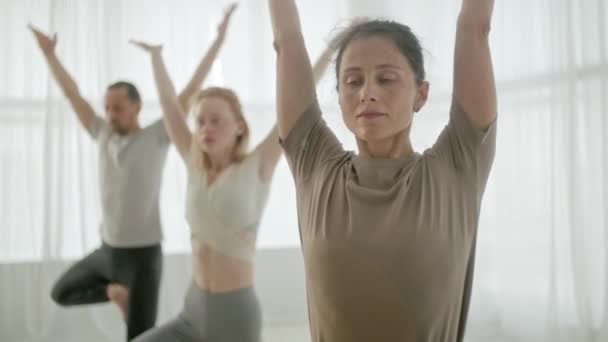 Clase de yoga Grupo de tres mujeres y hombres que ejercen un estilo de vida saludable en In Bright Studio. Gente balanceándose en una pierna en Bright Fitness Studio y clase de gimnasia. — Vídeos de Stock