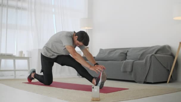 Deportivo Caucásico Hombre Entrenando, Haciendo Cross Fit Ejercicio Deportivo en Carpé Mientras Ver Fitness Video En Línea En Teléfono En Casa . — Vídeos de Stock