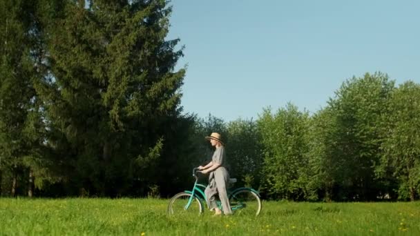 Glückliche junge Frau spaziert bei Sonnenaufgang mit dem Fahrrad auf der Landstraße. Schöne Frau am Boden Pfad Green Grass Field Spaß haben und das Leben genießen — Stockvideo