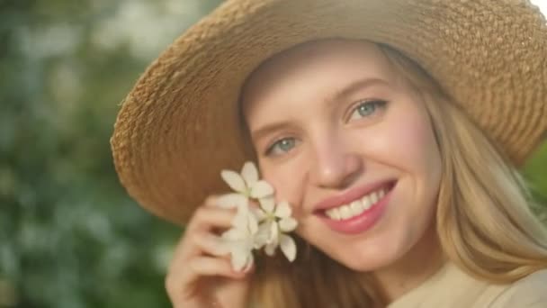 Egy fiatal, gyönyörű szőke nő portréja a Tavaszi Virágos Kertben. Boldog Gyönyörű Lány a Spring Parkban. Virágok nyílnak a fán. Nő pózol közel virág fa. — Stock videók